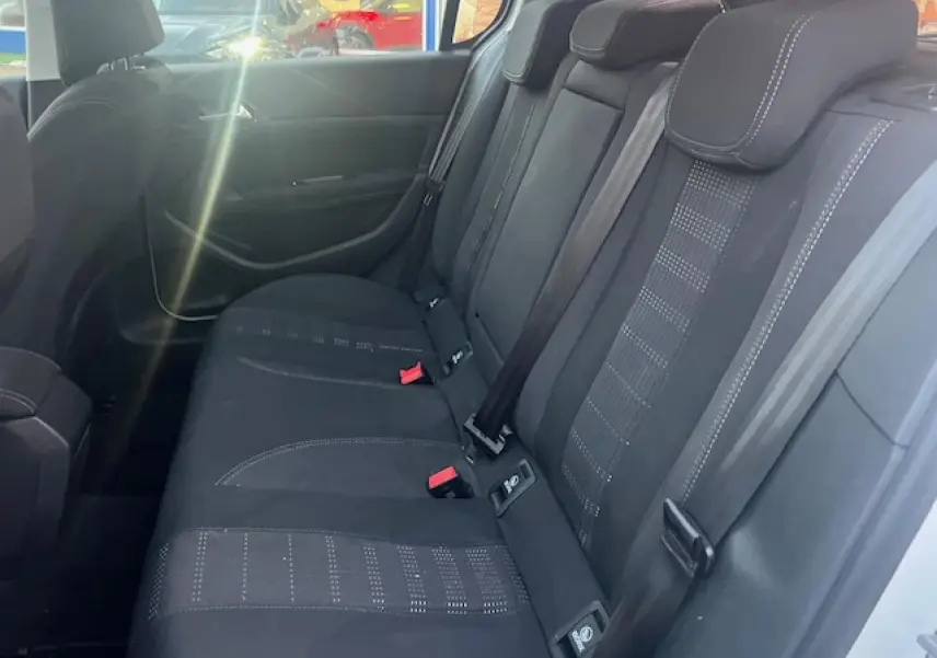 Vue intérieure côté droit montrant la banquette arrière noire avec appuie-têtes et ceintures de sécurité du Peugeot 308 blanc.