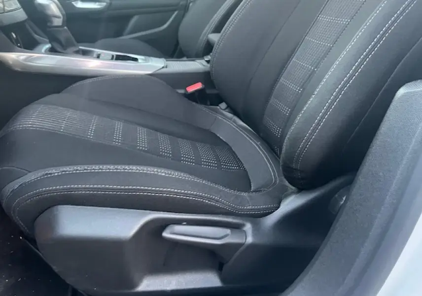 Gros plan sur le siège avant droit noir de la Peugeot 308 blanche, montrant les détails de la sellerie et la commande d'ajustement.