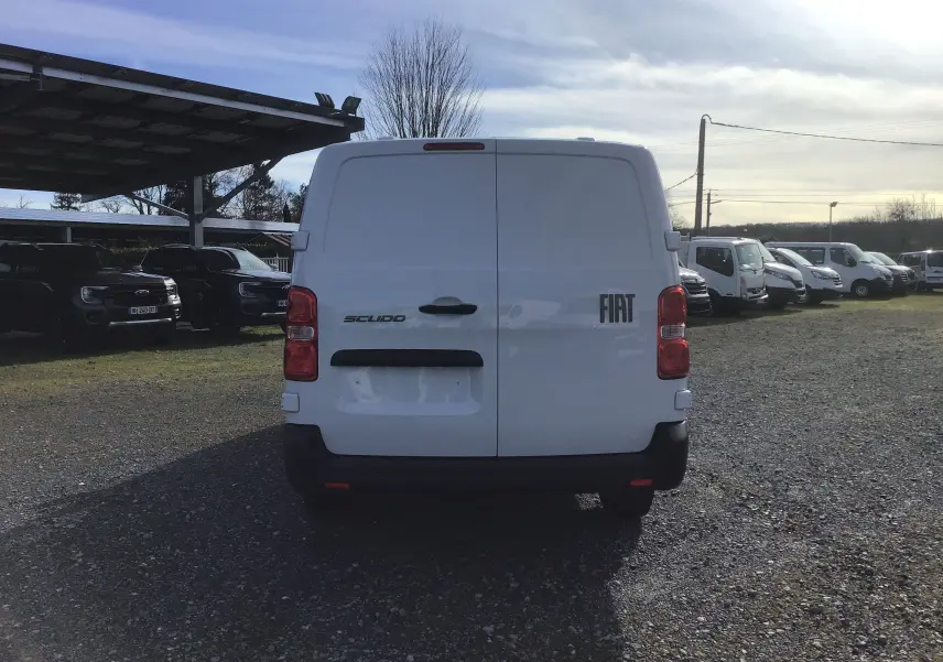 Vue arrière d'un FIAT Scudo Fourgon blanc 2024, avec portes battantes fermées et logo visible sur un parking extérieur.