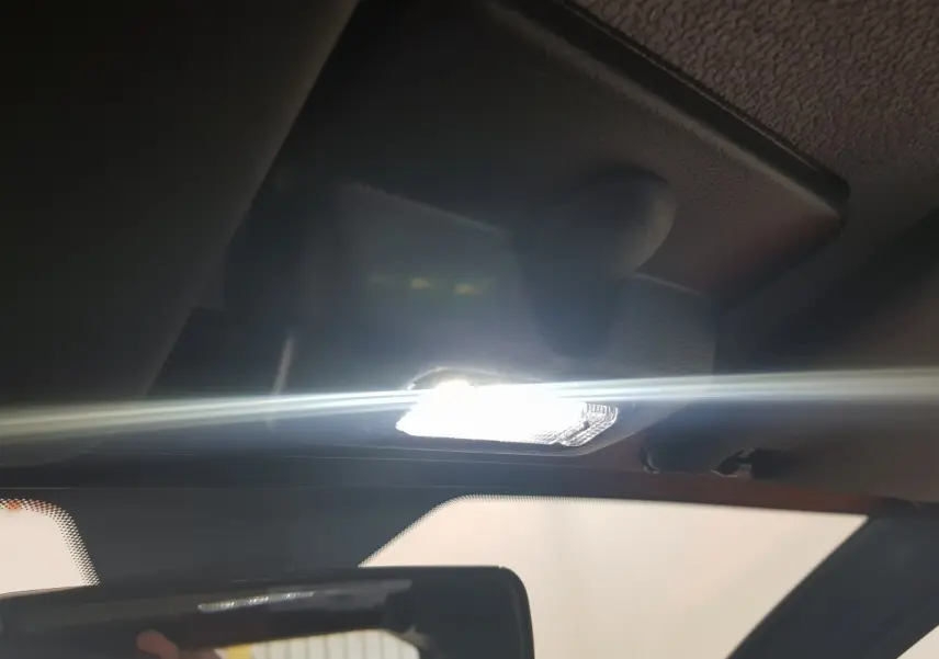 Plafonnier intérieur allumé vu de près sur l'AIXAM AMBITION 0.5 CITY PACK 2026 rouge, avec rétroviseur central visible.