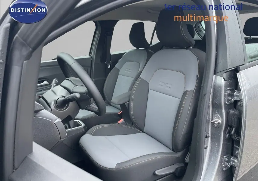 Vue intérieure côté conducteur de la Dacia Sandero Stepway 2024, sièges gris clair et foncé avec surpiqûres contrastées.