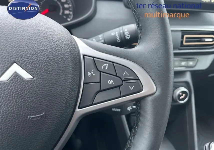 Gros plan sur le volant noir de la Dacia Sandero Stepway 2024, montrant les commandes multifonctions côté droit.