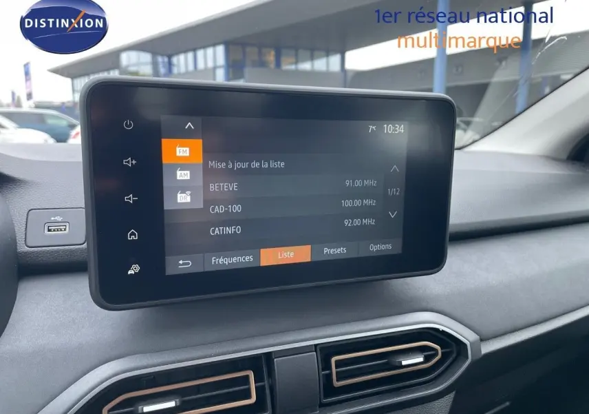 Écran tactile central affichant la liste des stations radio dans l'habitacle gris d'une Dacia Sandero Stepway 2024.