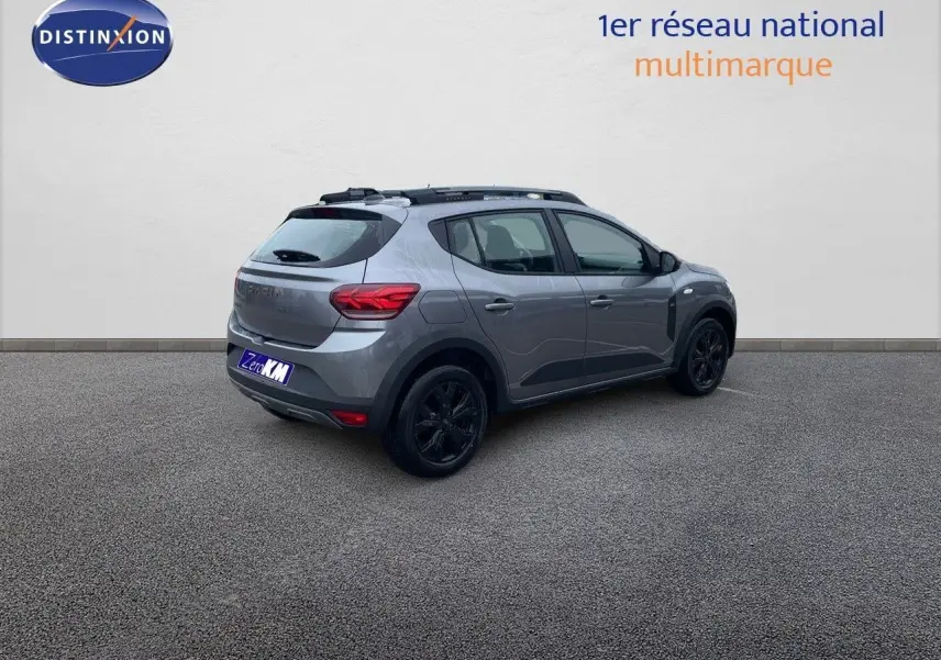 Vue 3/4 arrière droite d'une Dacia Sandero Stepway 2024 gris schiste métal avec jantes noires et toit noir.