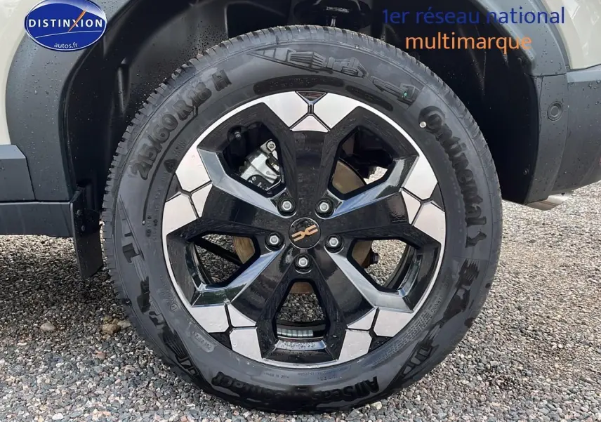 Gros plan sur la roue avant droite du Dacia Duster 2025 couleur Sandstone avec jante alu bicolore.