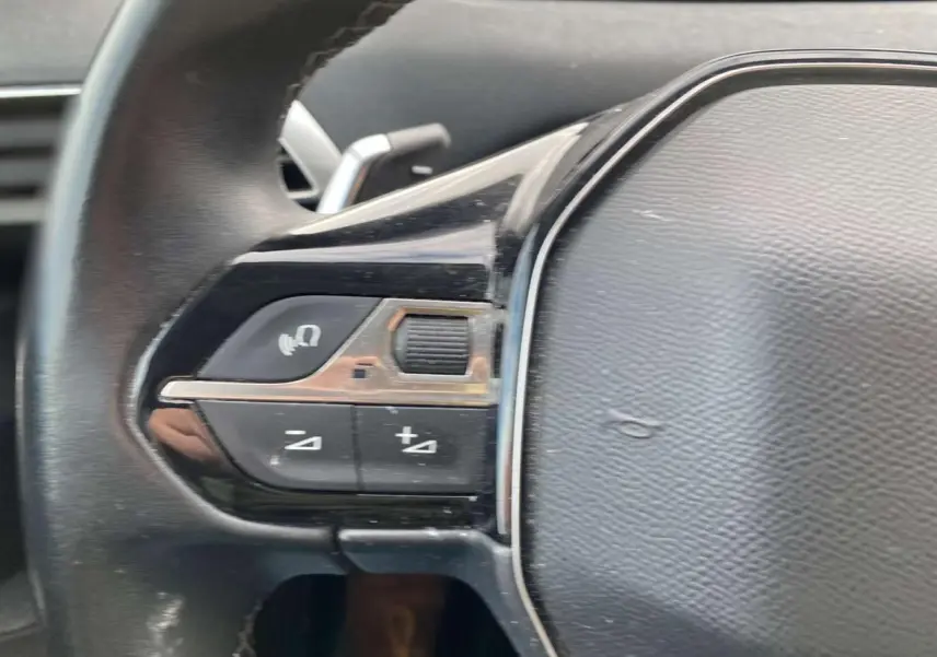 Gros plan sur les commandes gauche du volant noir du Peugeot 3008 Active 2019, avec boutons de volume et fonction vocale.