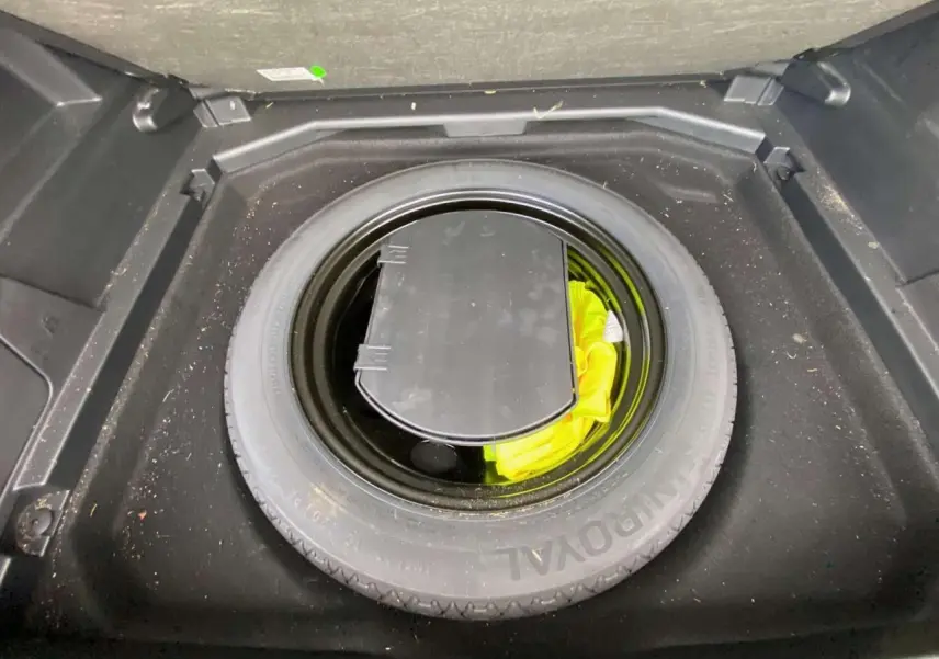 Vue plongeante sur la roue de secours noire et son rangement dans le coffre du Peugeot 3008 noir 2019.
