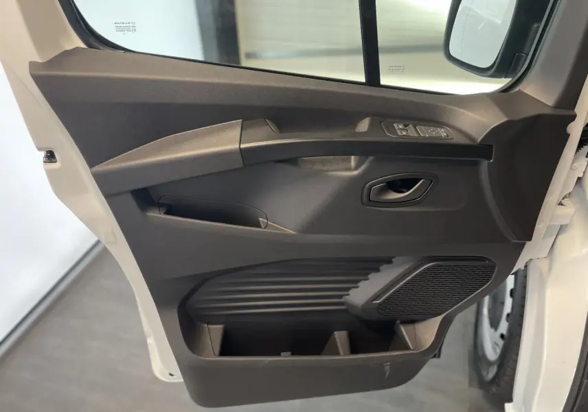 Porte côté conducteur ouverte du Renault Trafic Fourgon blanc, montrant les commandes de vitre et le haut-parleur intégré.