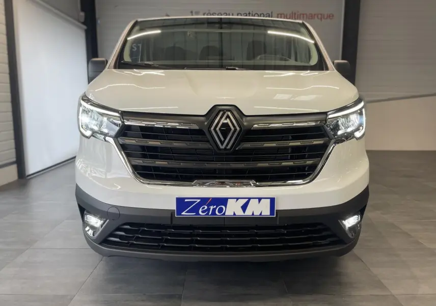 Vue frontale d'un Renault Trafic Fourgon blanc avec calandre noire et phares Full LED allumés en intérieur.