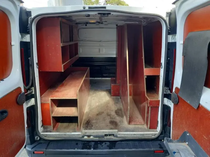 Vue arrière du Renault Trafic Fourgon blanc glacier 2019 avec aménagement intérieur en bois pour rangement.