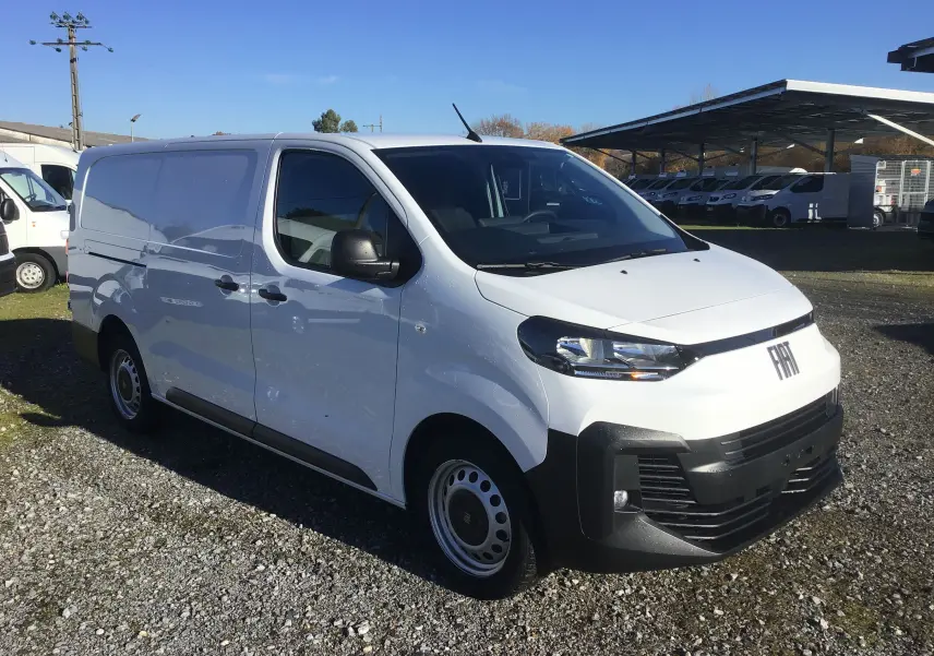 Fourgon FIAT Scudo XL blanc en 3/4 avant droit, avec pare-chocs noirs et calandre moderne sur un terrain extérieur.