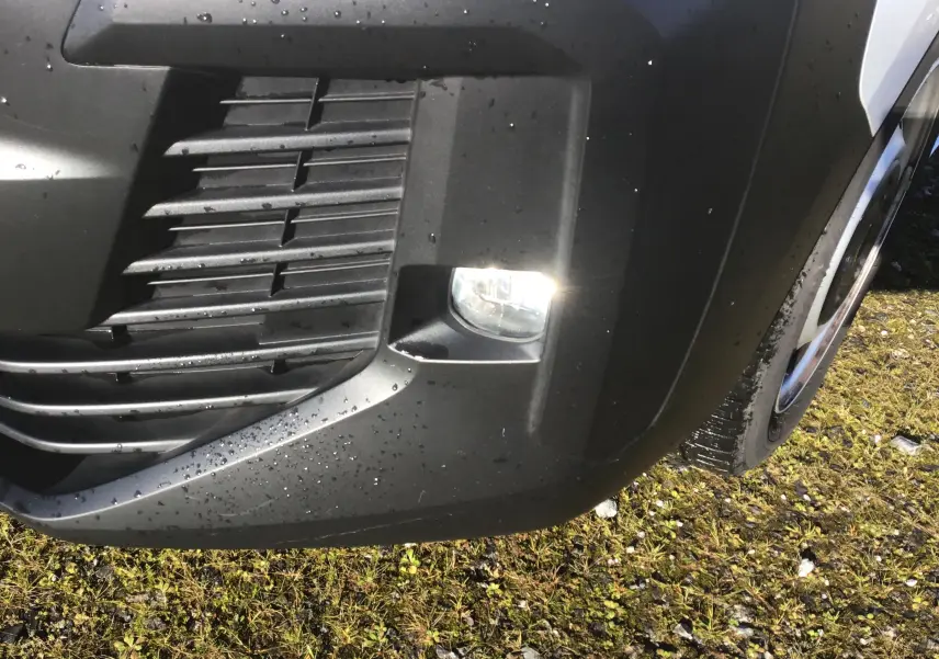 Gros plan sur le feu antibrouillard avant droit du FIAT Scudo Fourgon blanc avec pare-chocs noir et gouttes d'eau.