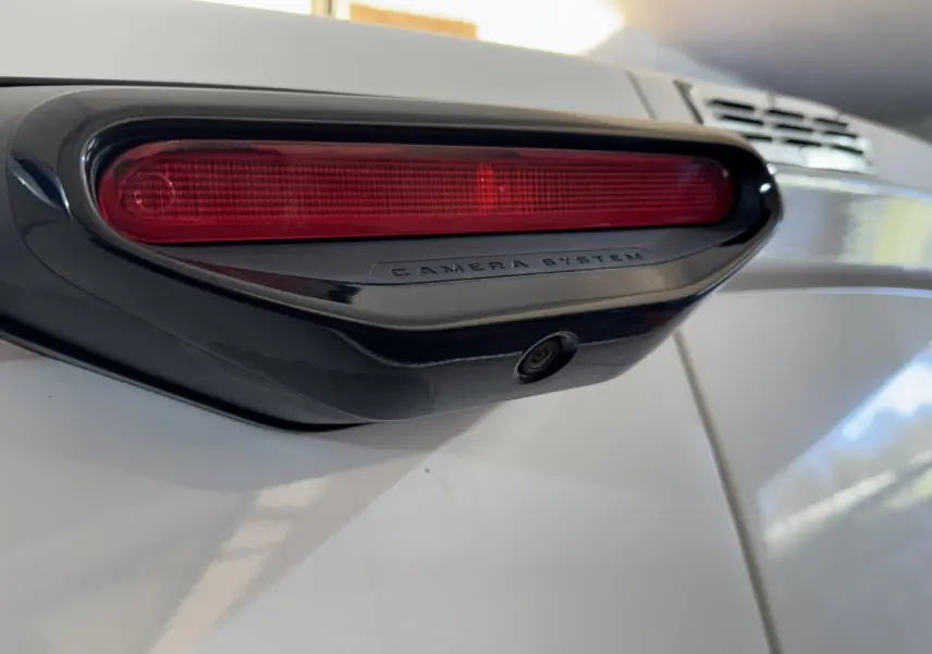 Gros plan sur la caméra de recul intégrée sous le troisième feu stop rouge du Citroën Berlingo blanc.