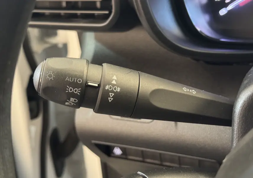 Gros plan sur la manette de commande des phares et clignotants du Citroën Berlingo blanc, vue côté conducteur.