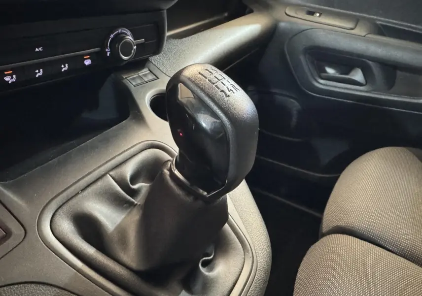 Gros plan sur le levier de vitesses manuel noir dans l’habitacle sombre du Citroën Berlingo blanc de 2020.