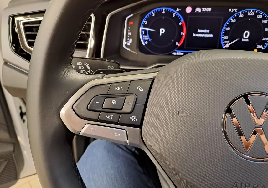 Gros plan sur le volant côté gauche du Volkswagen Taigo 2025, avec commandes de régulateur et tableau de bord numérique.