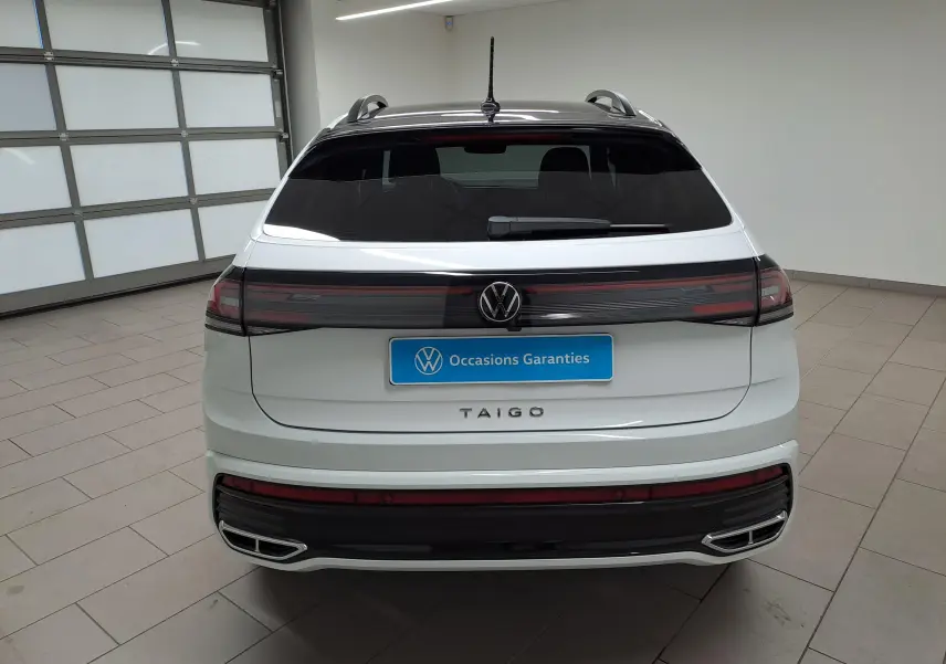 Vue arrière d'un Volkswagen Taigo blanc pur avec toit noir, feux arrière connectés et double sortie d'échappement chromée.