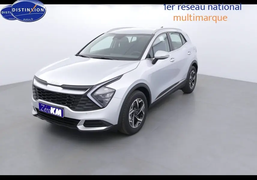 KIA Sportage gris acier métal vu en 3/4 avant droit, avec calandre noire et jantes bicolores distinctives.