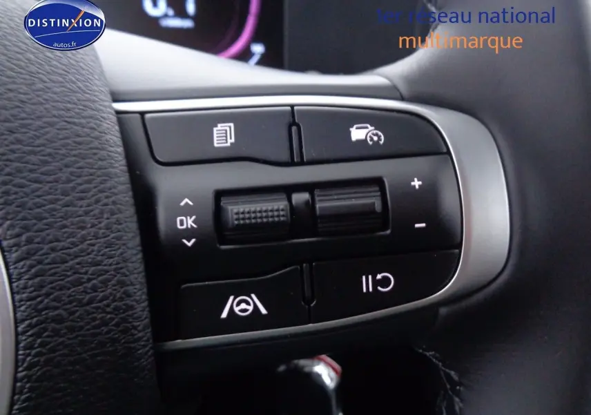 Gros plan sur les commandes au volant du Kia Sportage gris acier, mettant en valeur les boutons de régulateur et d’aide à la conduite.