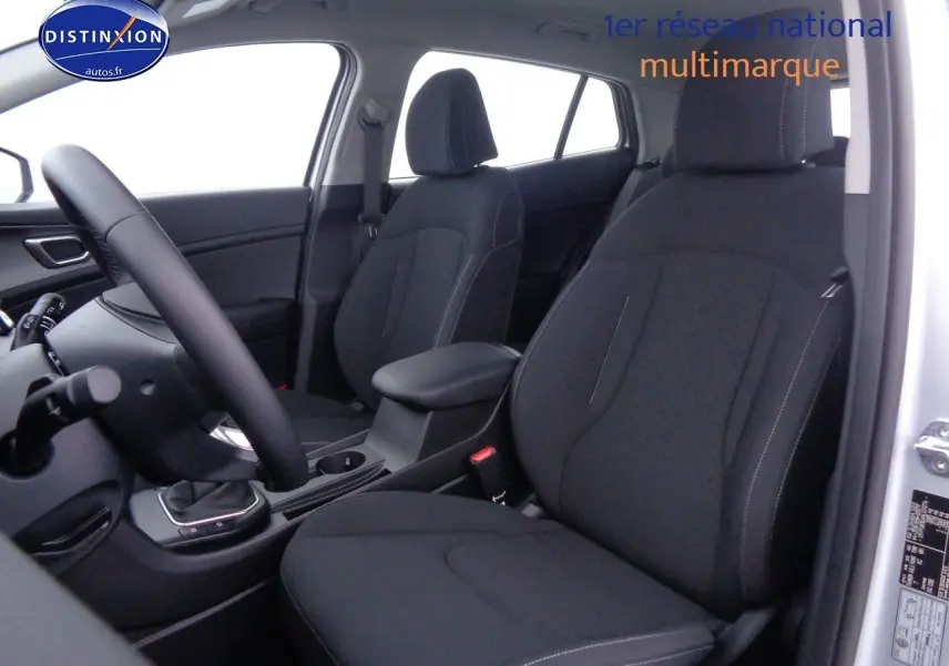 Vue intérieure côté conducteur du Kia Sportage gris acier 2022, sièges noirs avec coutures contrastées et console centrale.