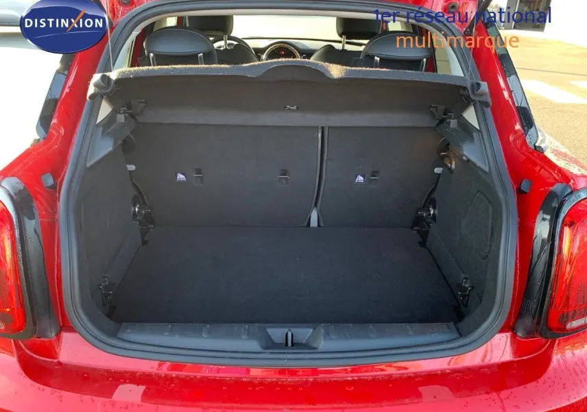 Coffre ouvert d'une MINI rouge chili 2023, vue arrière montrant l'espace de chargement et l'intérieur noir.