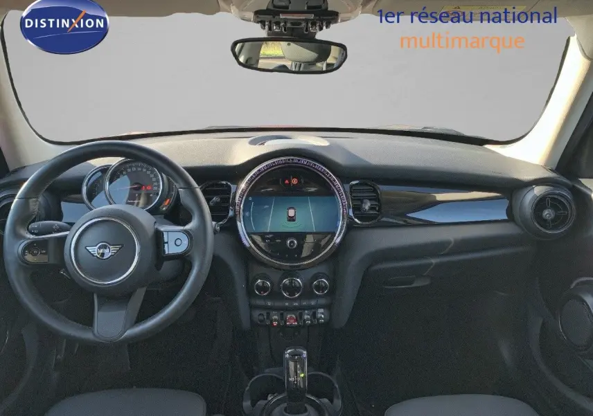 Vue intérieure frontale du tableau de bord de la MINI 1.5 136CH STEPTRONIC 2023 avec volant, écran central rond et finition noire.