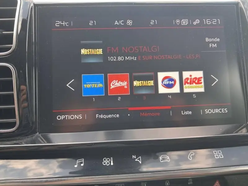 Écran tactile de la console centrale du Citroën C5 Aircross blanc, affichant les stations radio FM avec sélection sur Nostalgie.