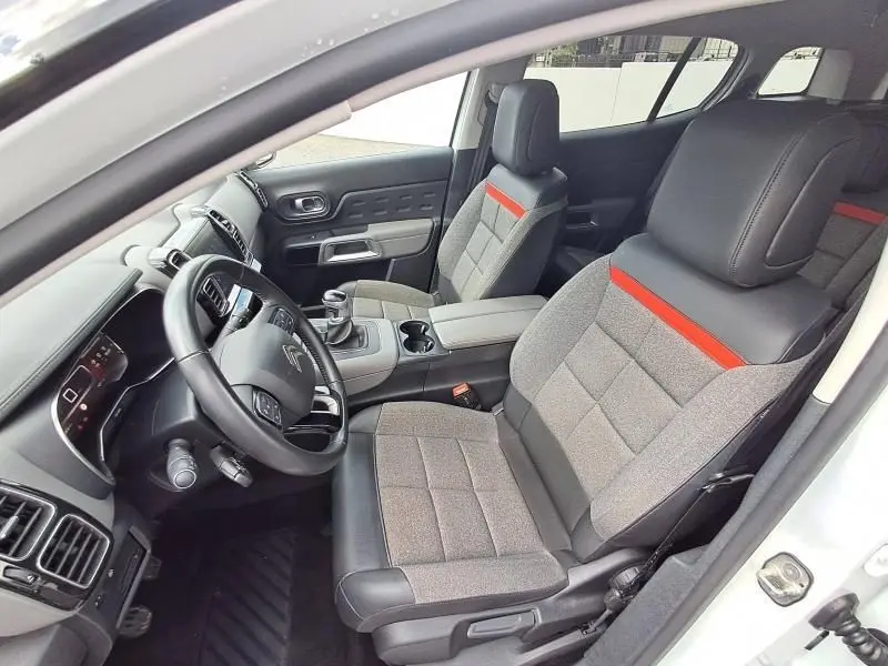 Intérieur avant du Citroën C5 Aircross blanc 2019, sièges tissu gris avec bande orange et volant multifonction.