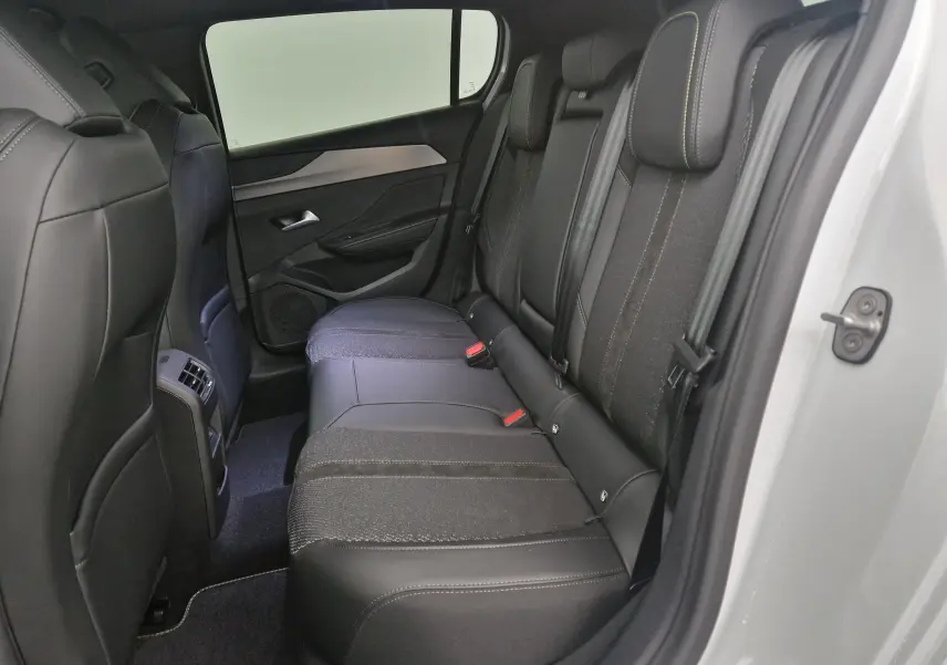 Vue intérieure côté droit des sièges arrière en tissu et cuir noir du Peugeot 308 blanc Okenite 2025.