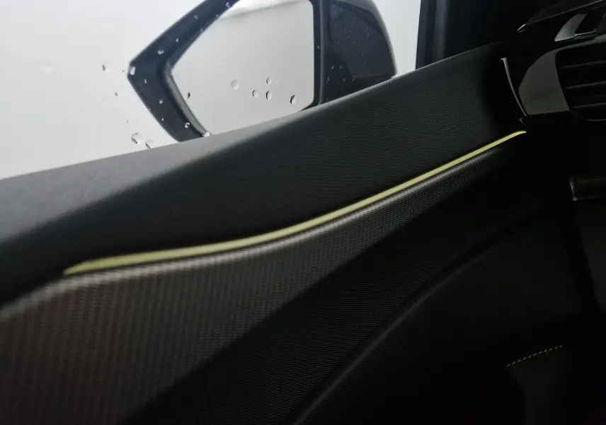 Détail de la garniture intérieure côté gauche avec surpiqûres claires et rétroviseur extérieur de la Peugeot 308 GT+ blanc Okenite.