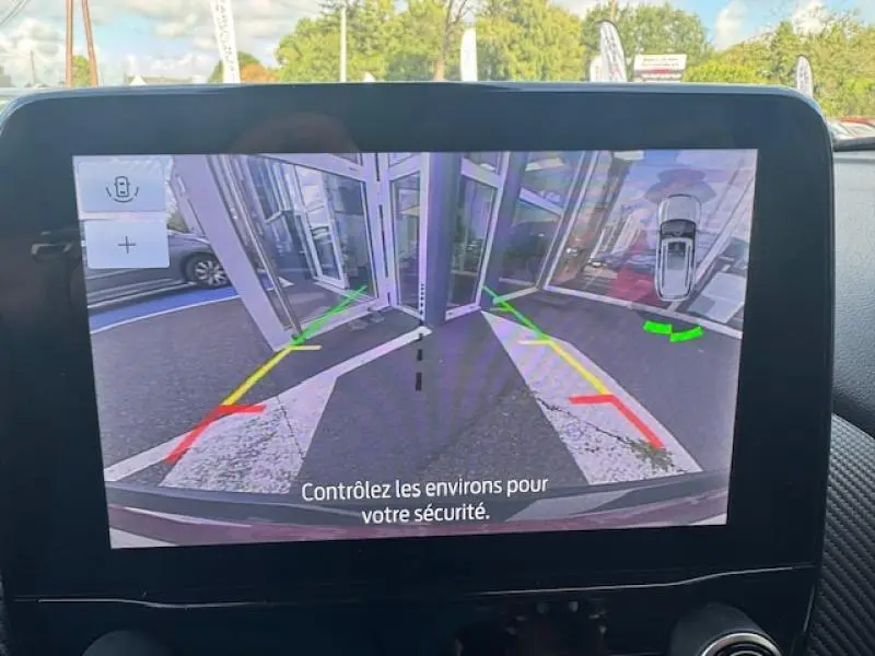 Écran tactile montrant la caméra de recul du Ford Puma rouge, avec lignes d’aide au stationnement et vue arrière.