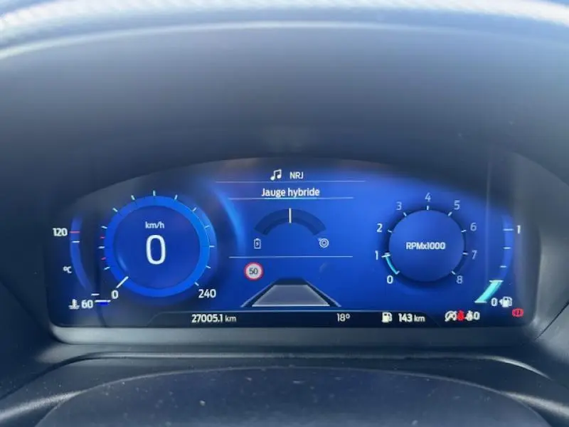 Tableau de bord numérique bleu du Ford Puma 2023 affichant vitesse, compte-tours et jauge hybride en gros plan.