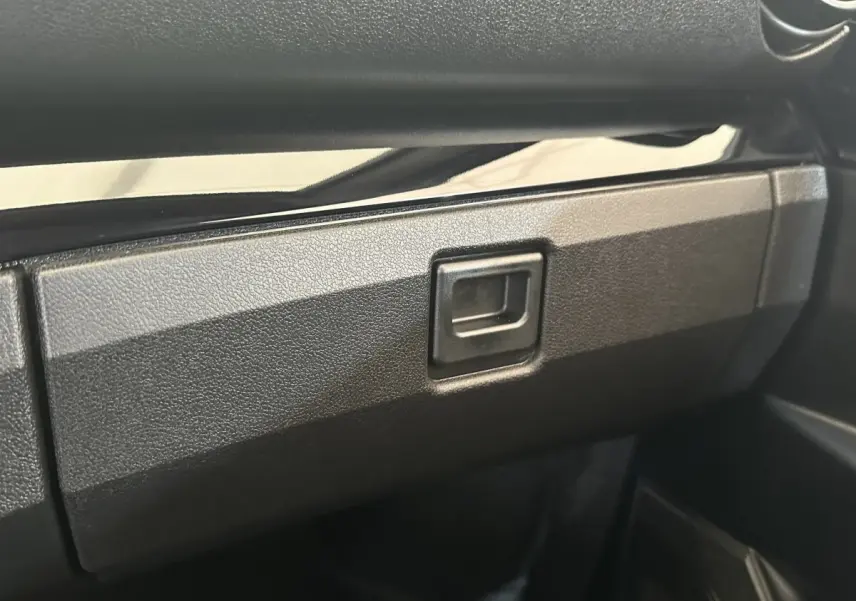 Gros plan sur la boîte à gants noire à l'intérieur de l'AIXAM AMBITION 0.5 CITY SPORT 2026.