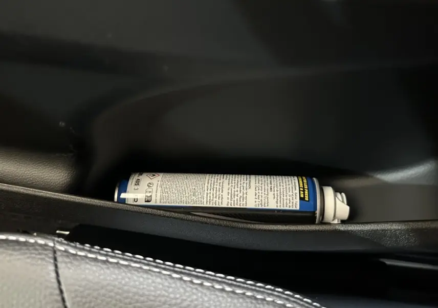 Gros plan sur le rangement intérieur côté conducteur de l'AIXAM AMBITION 0.5 CITY SPORT 2026 avec un spray posé.