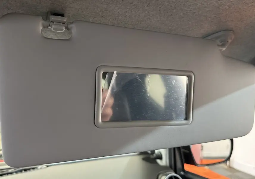 Détail du pare-soleil gris avec miroir intégré côté conducteur de l'AIXAM AMBITION 0.5 CITY SPORT rouge, vue intérieure.