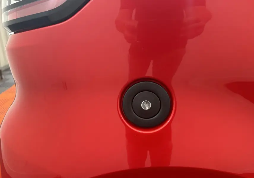 Détail du bouchon de réservoir noir sur la carrosserie rouge de l'AIXAM AMBITION 0.5 CITY SPORT, vue rapprochée.