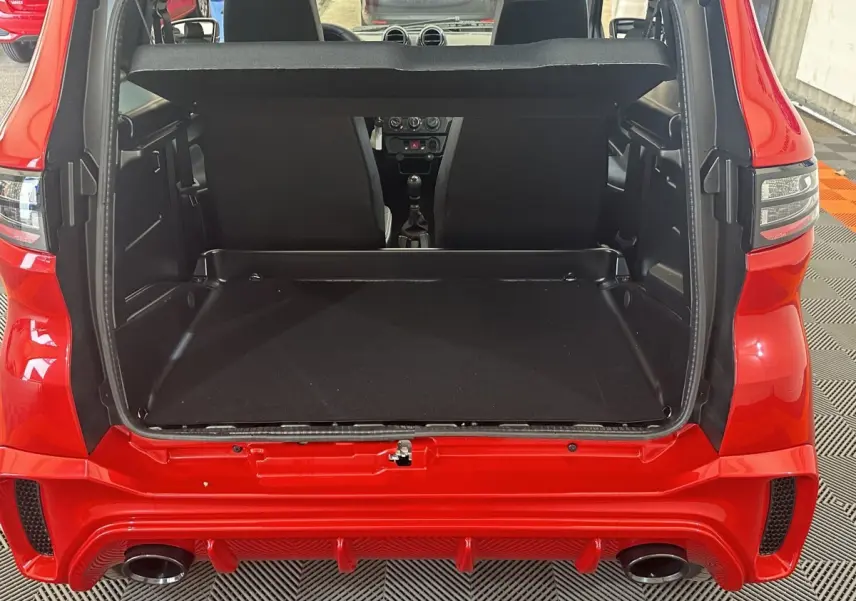 Vue arrière ouverte du coffre de l'AIXAM AMBITION 0.5 CITY SPORT rouge 2026 avec intérieur noir et banquette avant visible.