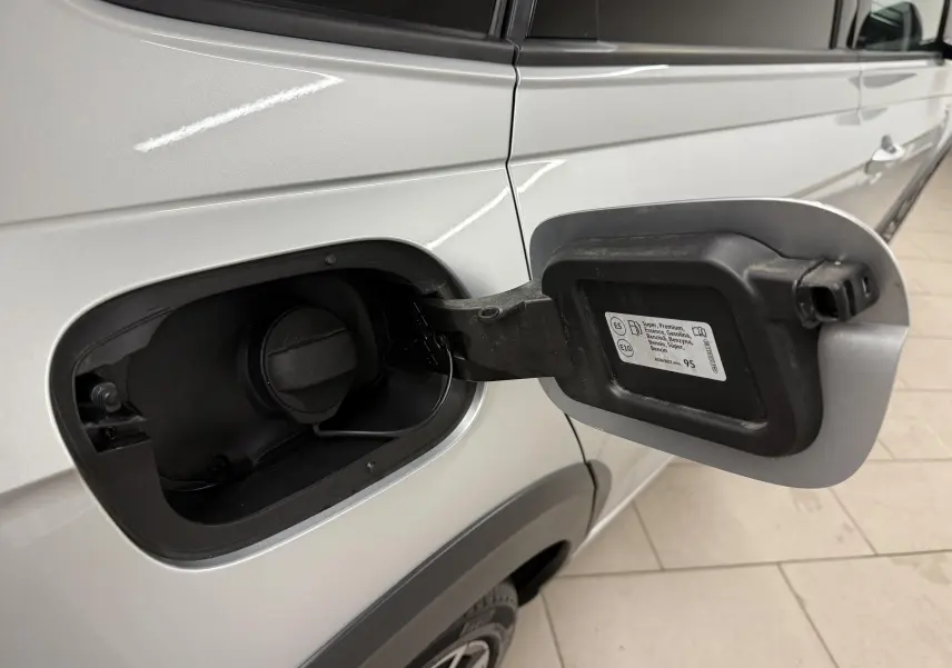 Vue rapprochée du volet de remplissage carburant ouvert côté gauche d’un Volkswagen Taigo argent métallisé avec toit noir.