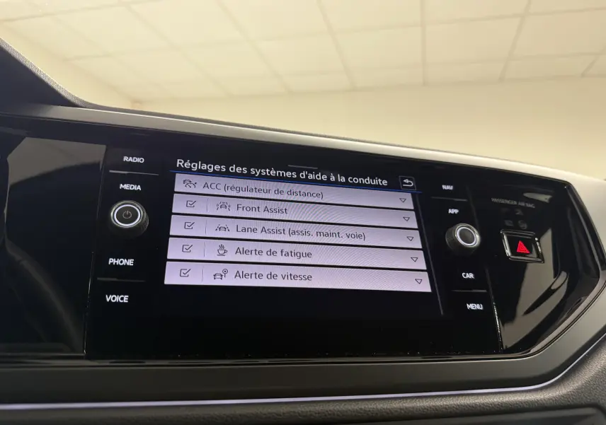 Écran tactile central du Volkswagen Taigo 2025 affichant les réglages des aides à la conduite, intérieur noir.