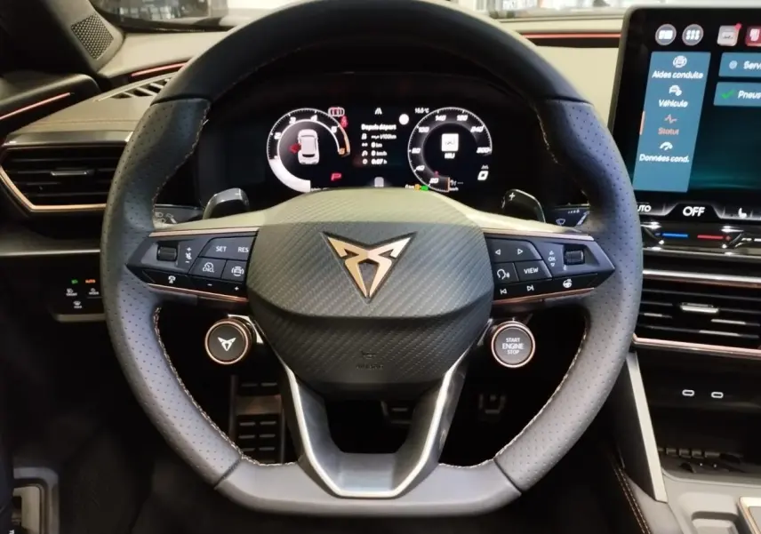 Vue rapprochée du volant noir perforé Cupra avec logo cuivré et tableau de bord digital du Formentor 1.5 eTSI Hybrid.