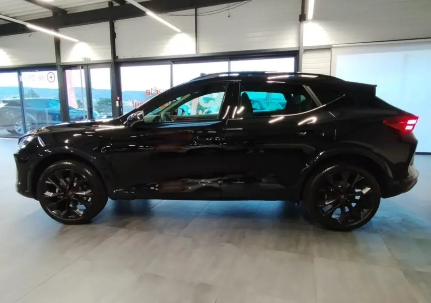 Profil droit d'un CUPRA Formentor noir métal 2026 avec jantes alliage noires et vitres teintées en intérieur showroom.