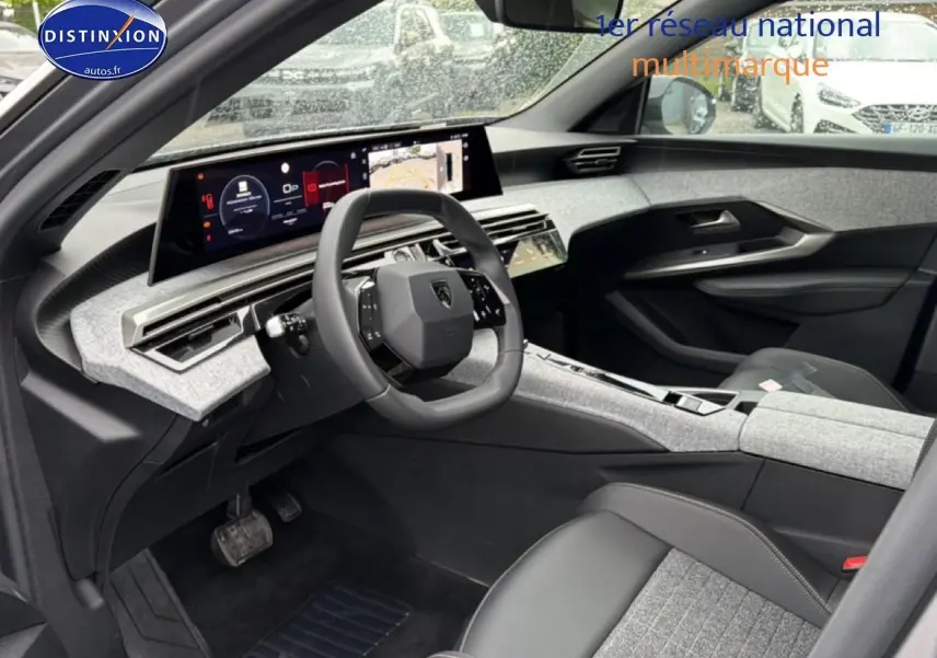 Vue intérieure côté conducteur du Peugeot 5008 Hybrid 145 allure e-dcs6 2025 avec tableau de bord gris et volant cuir noir.