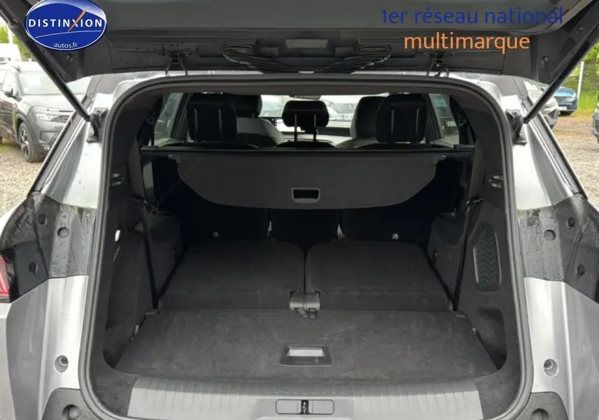 Coffre ouvert vu de l'arrière d'un Peugeot 5008 gris artense avec banquette arrière rabattue à plat.