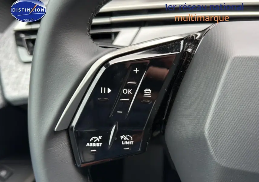 Gros plan sur les commandes multifonctions noires à gauche du volant cuir du Peugeot 5008 gris Artense 2025.