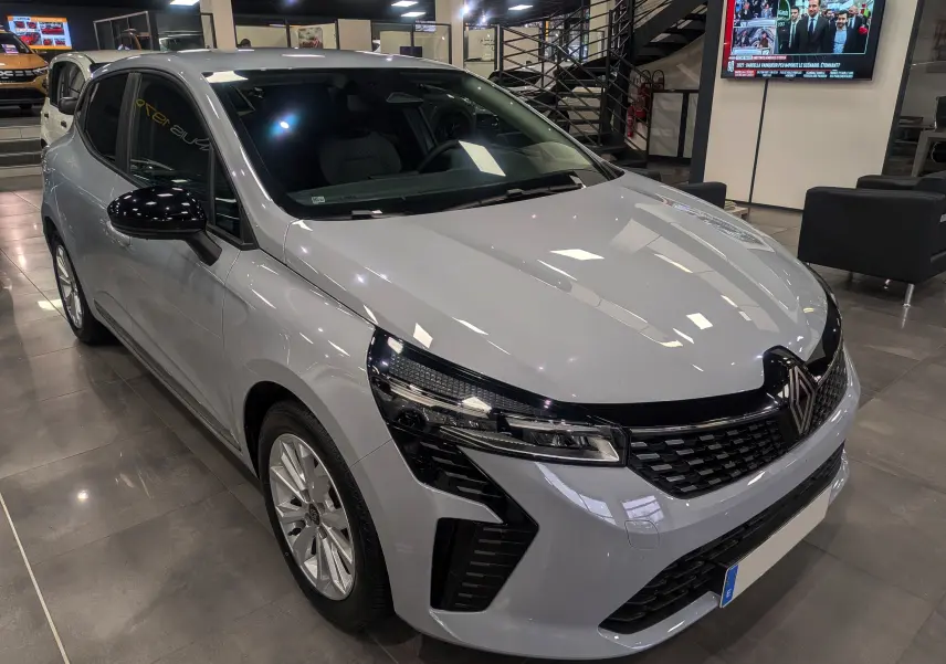 Renault Clio V Blue dCi 100 en gris Rafale, vue 3/4 avant droit dans un showroom lumineux.