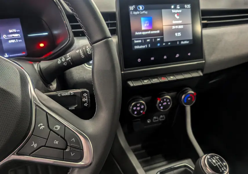 Vue intérieure de la Renault Clio V Blue dCi 100 en gris, montrant le volant, la boîte manuelle et l'écran tactile central.