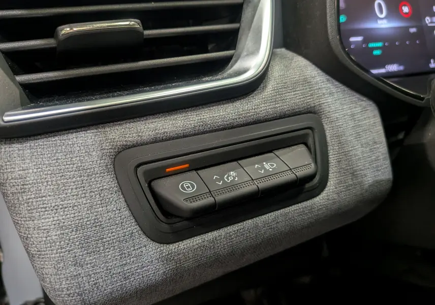 Gros plan sur les commandes d'éclairage et de verrouillage intégrées dans la garniture grise du tableau de bord Renault Clio V 2025.