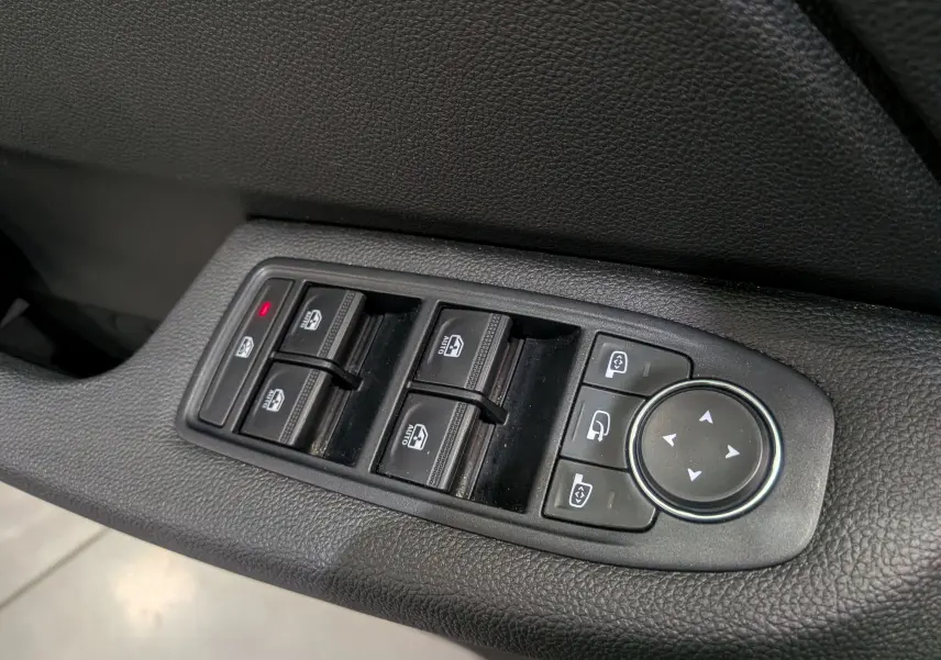 Gros plan sur les commandes des vitres électriques et réglages des rétroviseurs côté conducteur d'une Renault Clio V Gris Rafale.