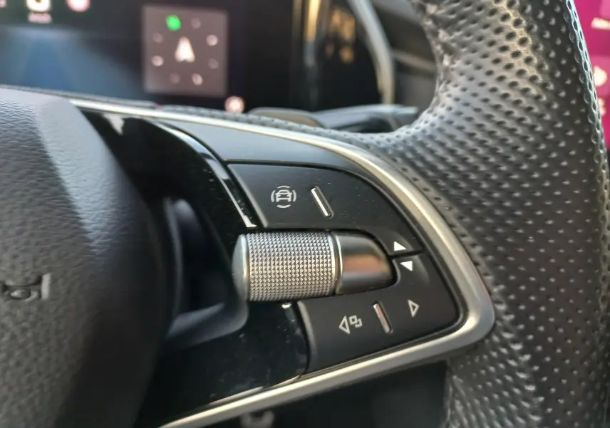 Gros plan sur les commandes gauche du volant perforé du Skoda Kodiaq Bleu RS 2024, avec molette métallique.