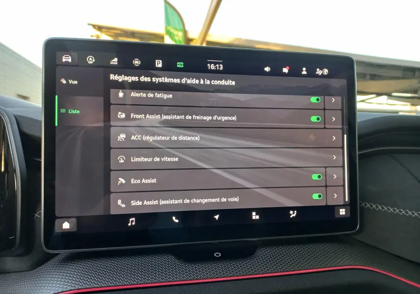 Écran tactile central du Skoda Kodiaq 2024 affichant les réglages des aides à la conduite, avec finition intérieure noire et surpiqûres blanches.